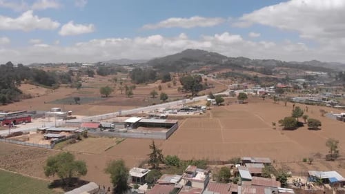 A slow motion drone shot over a rural town in Guatemala on a bright day.