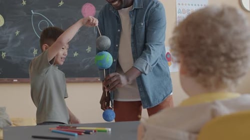 Boy with Teacher Holding a Solar System Model