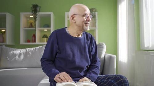 Senior Man Reading a Book on a Sofa