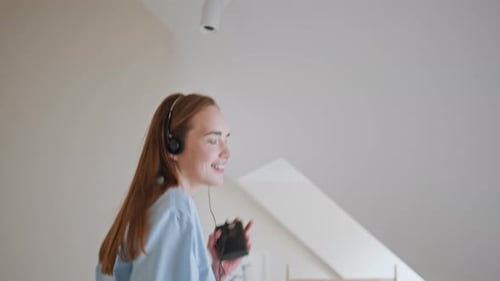 Woman Dances Joyfully on Bed with Headphones