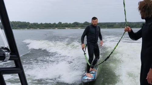 Man Wake Surfing behind Boat on a River