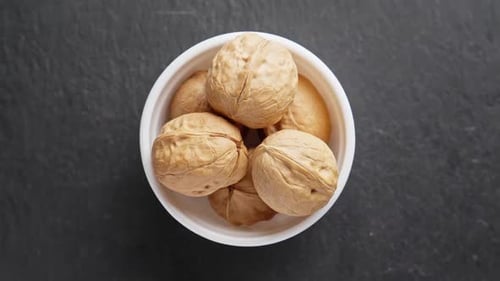 Walnuts in White Bowl on Dark Surface