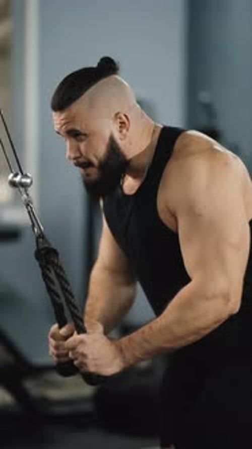 Muscular Athlete Performing Face Pulls on Crossover Machine Targeting Back Muscles with Focused