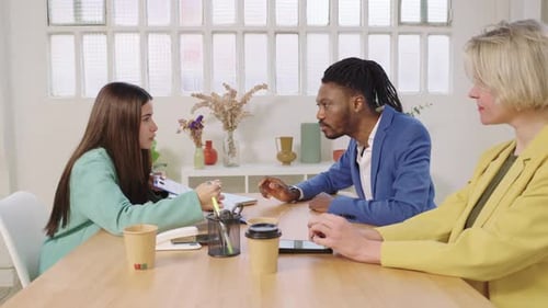 Three Adults in Colorful Blazers Discussing Business