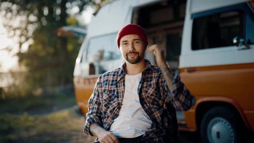 Bearded Man Sitting Next to Camper Van at Sunset