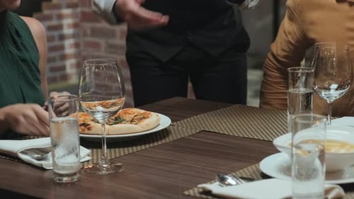 Waiter Serving Food for Guests in Restaurant