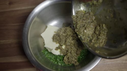 A chef preparing a café de paris sauce. Mixing all ingredients in a metal bowl. No face.