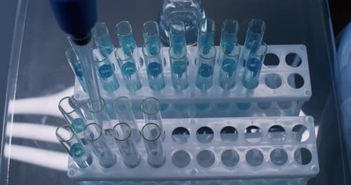 Lab Test Tubes with Blue Liquid Being Filled