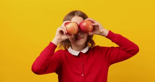 Stylish Smiling School Teenage Girl Holding Apples in Front of Her Eyes