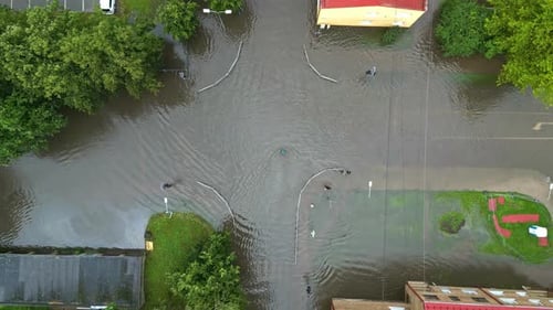 Drone aerial bird's-eye view of hazardous rainwater flooding across road street intersection in vill