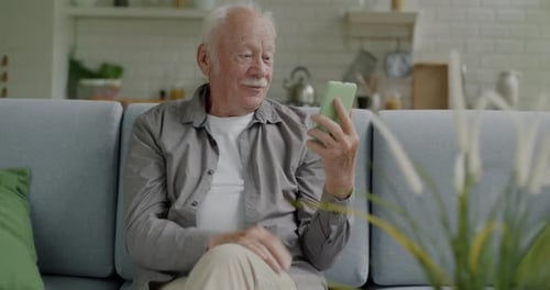 Senior Man Video Chats on His Phone at Home