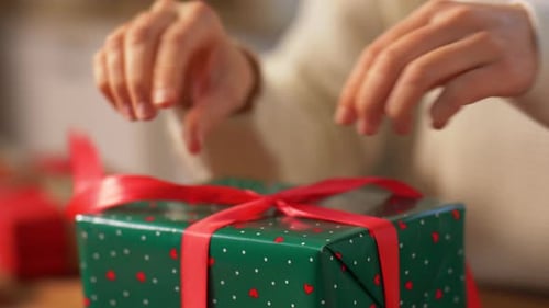 Hands Tying Festive Red Ribbon on Wrapped Gift