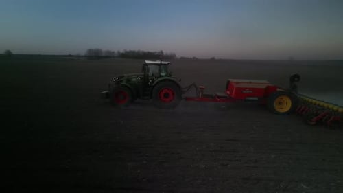Green tractor works on the field sowing sunflower. Tractor planting corn in Ukraine