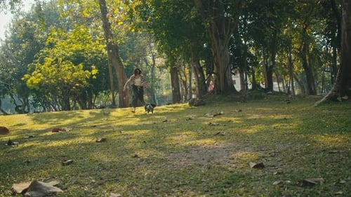 Woman Running With Dog on Green Grassy Hill