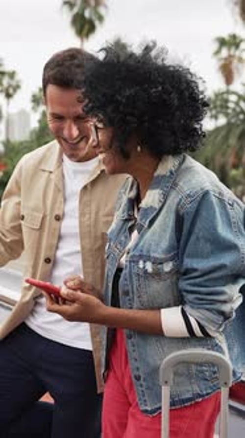 Pareja que comparte medios en una aplicación de teléfono celular en línea en la ciudad Mujer afroamericana con un amigo