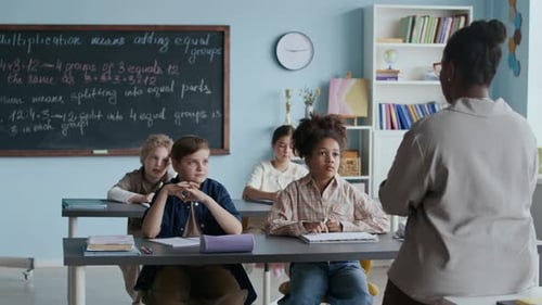 Teacher Explains Lesson to Diverse Students in Classroom