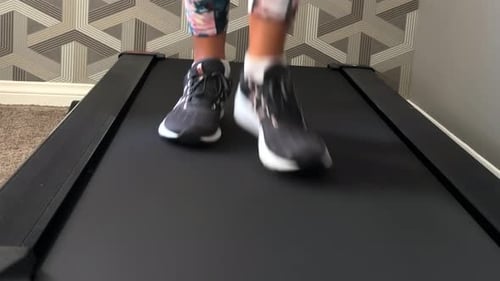 Woman walking on treadmill in home gym, close up of feet