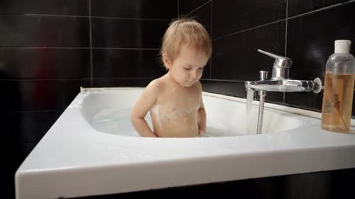 Blond Child Bathing in White Tub