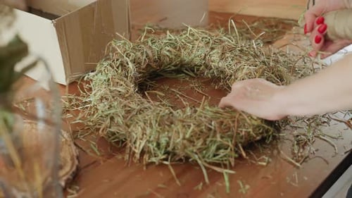 Hands Crafting Hay Wreath with Twine on Table