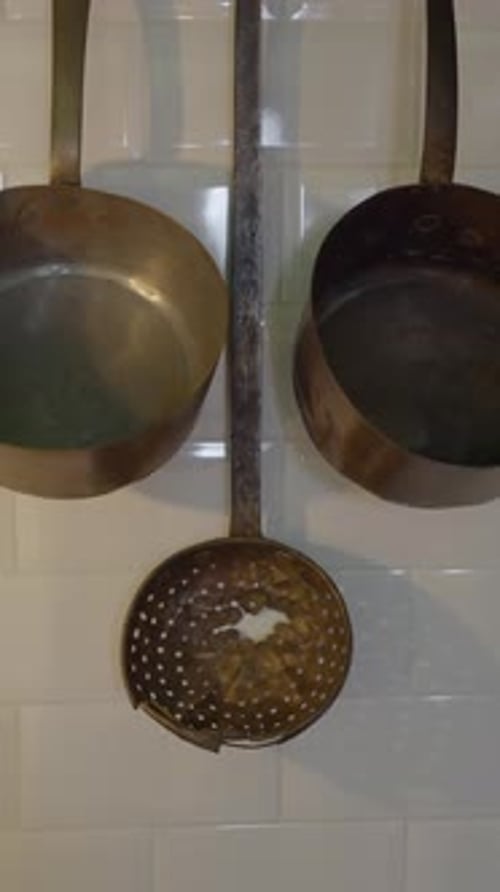 Pushout Shot of Metal Pots Hanging on White Tile Kitchen Wall