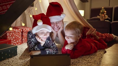 Family in Santa Hats Watching Tablet Together Indoors