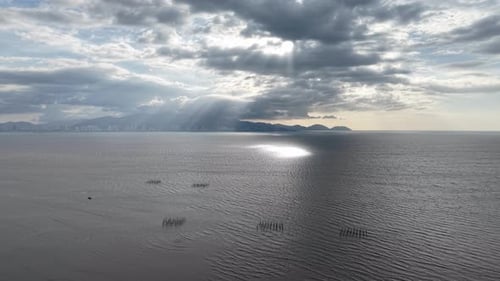 Aerial coastal view of ocean sunbeams over distant city