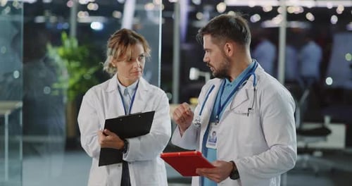 Two Medical Specialists Discussing Hospital Patiens Writing Down Report Looking Through Papers