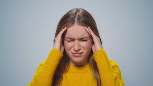 Woman with Headache Massaging Temples in Studio