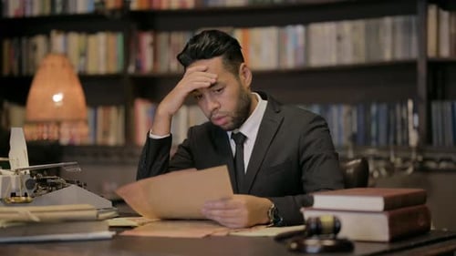 Concerned Man Reads Paperwork at Desk with Gavel