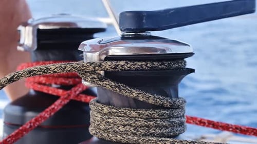 Closeup of yacht crew handling ropes on winch during navigation at sea