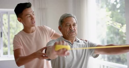 Senior Man Assisted with Resistance Band Exercise at Home