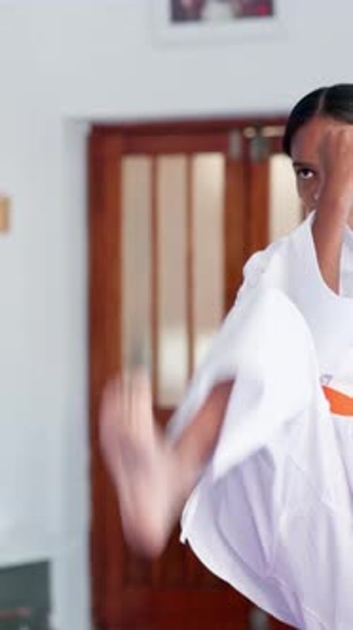 Girl Practices Karate Kicks in a White Gi