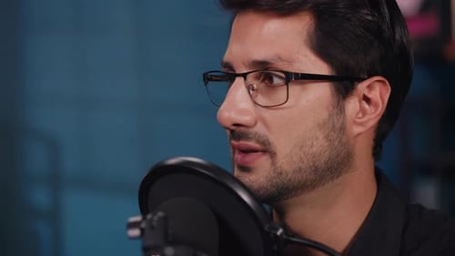 Portrait of Young Man in Glasses Conducts Podcast in Audio Recording Studio
