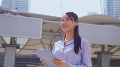 Asian young businesswoman using digital tablet while standing in the city