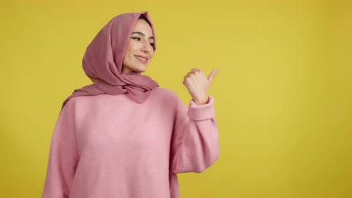 Muslim Woman Smiling at Camera and Pointing to the Side