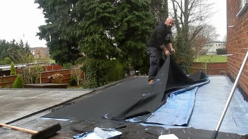 Man Repairs Roof in Suburban Home Setting