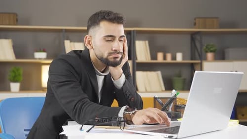Tired Man Working at Laptop in Office