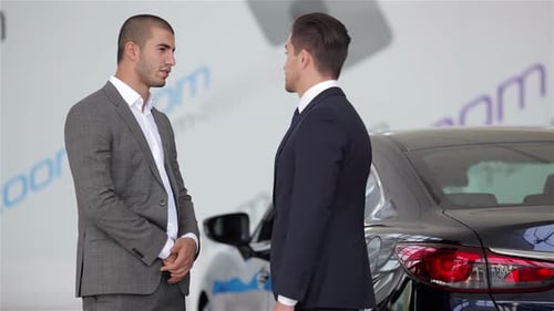 Two Men Wearing Suits Shake Hands in Dealership