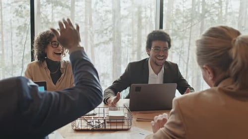 Startup Team Doing High Fives and Celebrating Success at Office Meeting