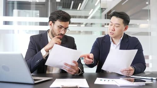 Professional business meeting between two male colleagues in modern office, discussing important