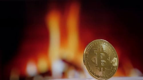 Gold Bitcoin Cryptocurrency Coin in Front of a Fire