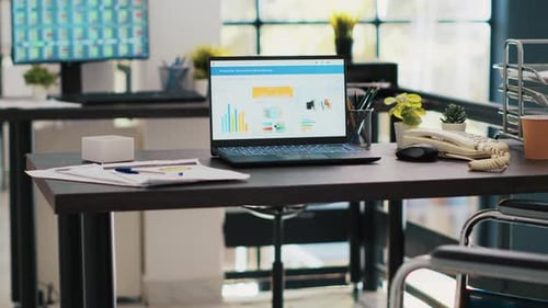 Wheelchair in Office with Laptop on Desk Showing Business Analytics