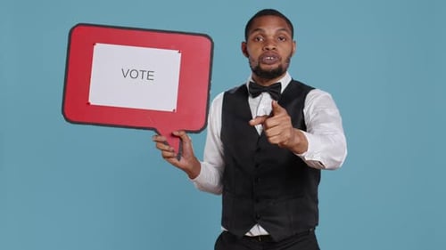 Man Holding Vote Sign Points to the Camera