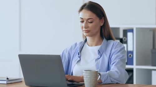 Junge Frau arbeitet tagsüber in einem modernen Büro an einem Laptop