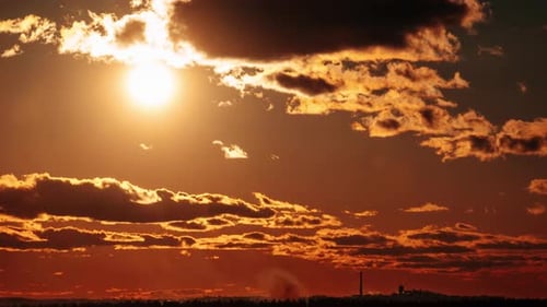 Bright Orange Sun Shines Through Clouds at Sunset