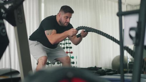 Adult Man Exercising with Ropes in Fitness Center