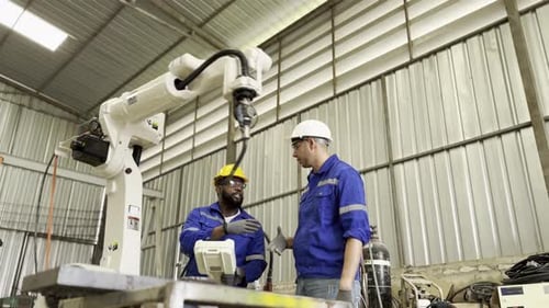 Engineers Working on Robot Arm Inside Factory