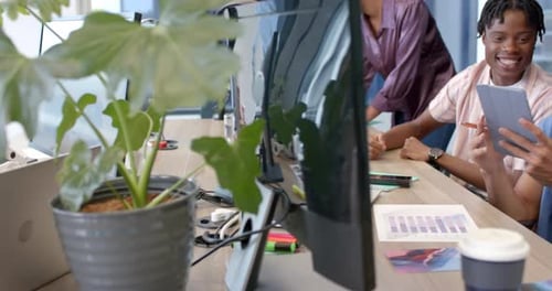 Collaborating on project, diverse team using tablet and laptop in modern office