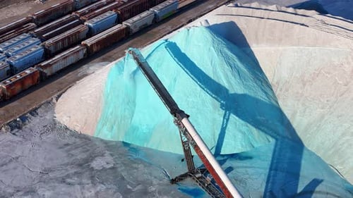 Conveyor distributing salt to large pile near railcars at Detroit salt depot in aerial view