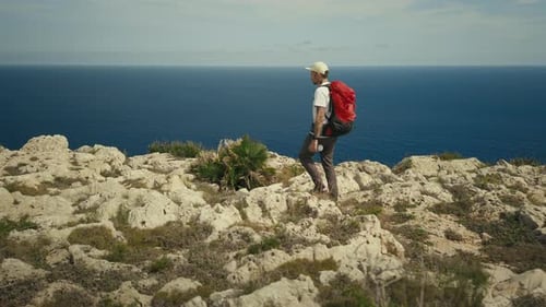 Man with Backpack Hike on Ridge of Mountain Cliff
